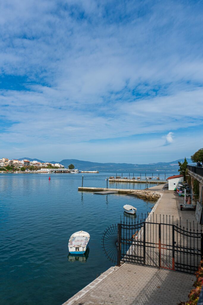 Explore a tranquil coastal landscape with boats, a wharf, and clear blue skies.